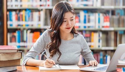 Student taking notes at the computer